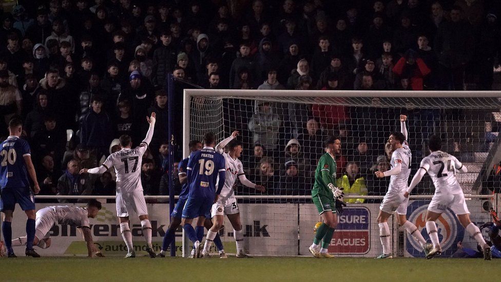 Newport County's James Clarke (on the ground) scores their side's second goal of the game during the Emirates FA Cup third round replay match at the Silverlake Stadium, Eastleigh