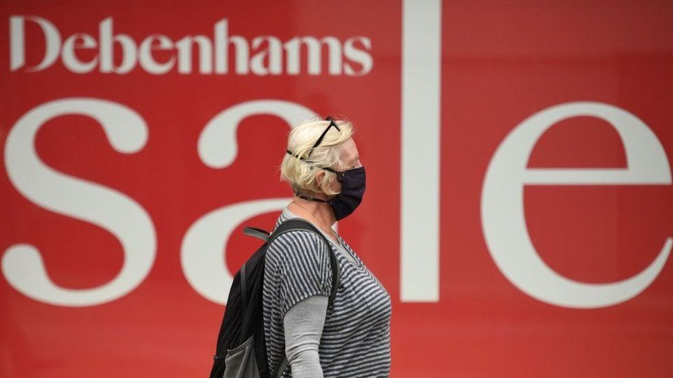 Masked woman in front of Debenhams sale sign