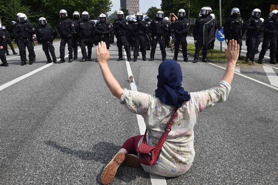 A demonstrator holds her hands up as she faces policemen during a protest on July 7, 2017 in Hamburg, northern Germany, where leaders of the world's top economies gather for a G20 summit
