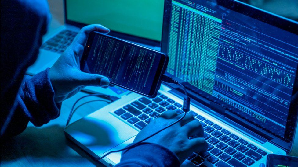 Hacker with computers in dark room.
