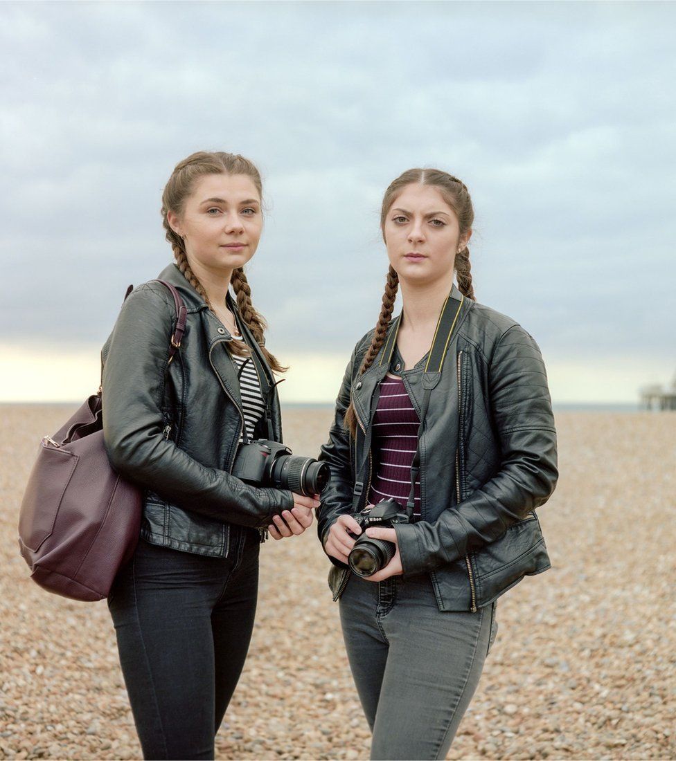 Two girls standing on a beach holding cameras