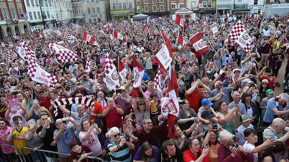 A crowd of people, many wearing Cobblers scarves