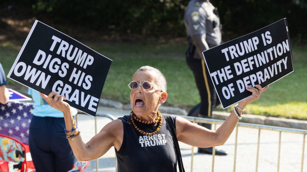 Protestor Laurie Arbeiter waves signs outside of the Fulton County Jail ahead of former President Donald Trump's surrender on 24 August2023 in Atlanta, Georgia