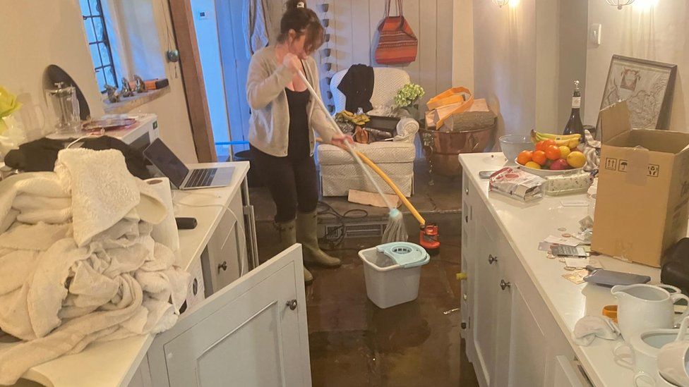 A woman mopping flood water in her Wiltshire home