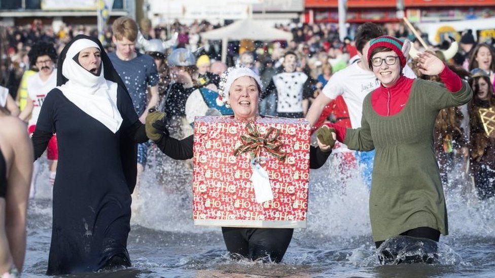 People take part in the Scarborough Lions New Year's Day Dip on Scarborough beach in Yorkshire