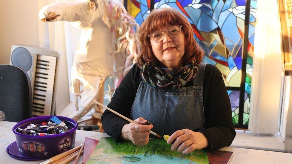 A woman sitting at a table holding a paintbrush