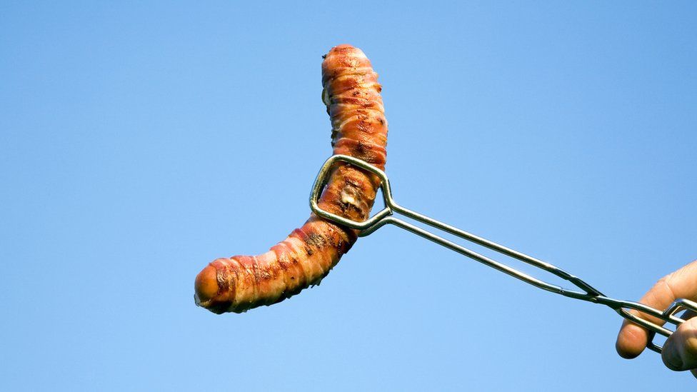 cooked sausage on BBQ tong