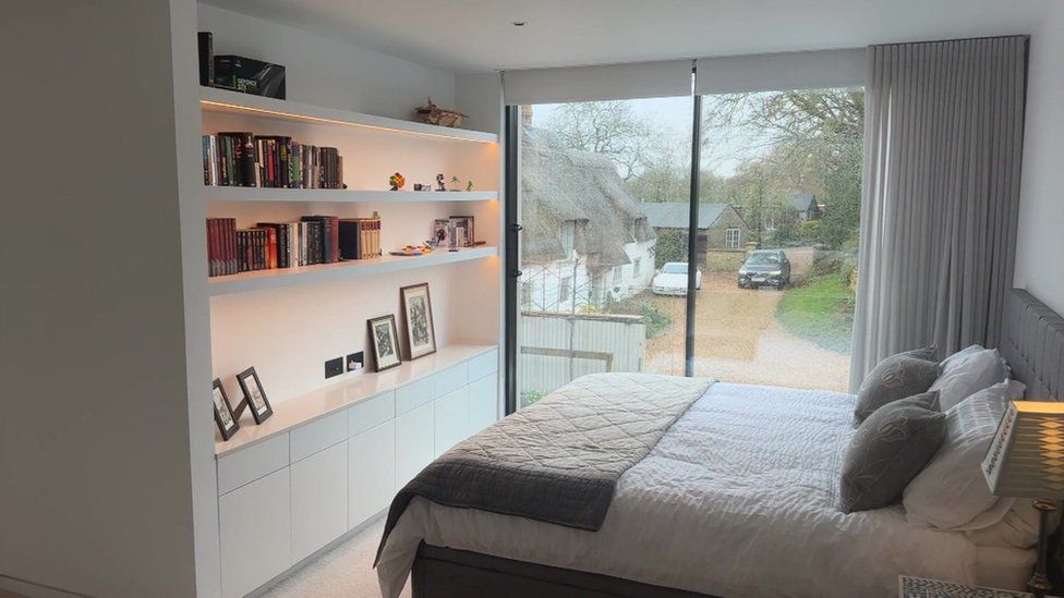 Bedroom showing large windows, bed and bookshelves