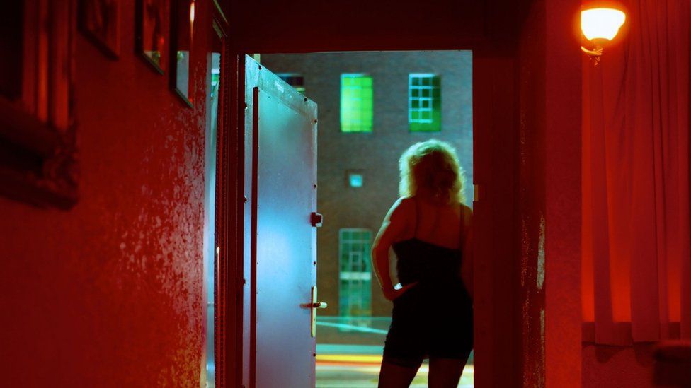 A woman stands at the door of a hotel room