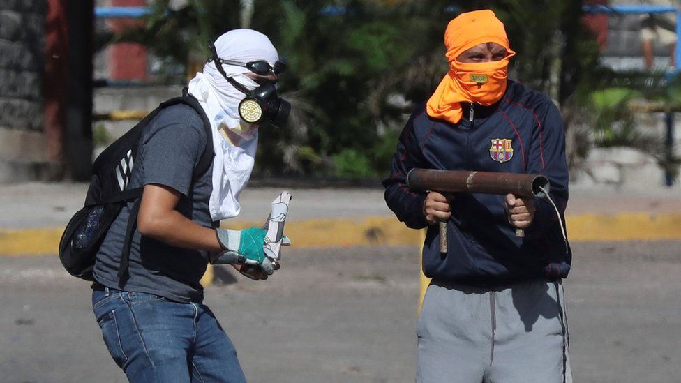Protesters throw projectiles at military police officers during clashes, in Tegucigalpa