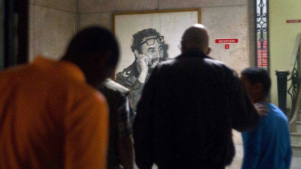 Cubans gather in front of a portrait of Fidel Castro