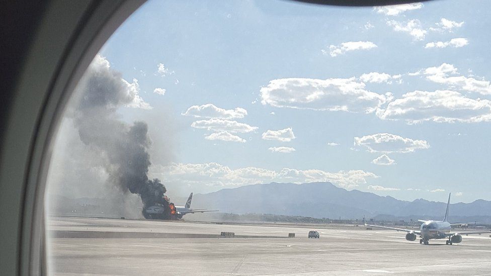 The view of a plane window, smoke billows out from a plane that caught fire at McCarren International Airport, 8 September 2015