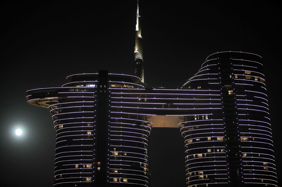 The moon rises in the sky behind world's tallest building of Burj Khalifa in Dubai