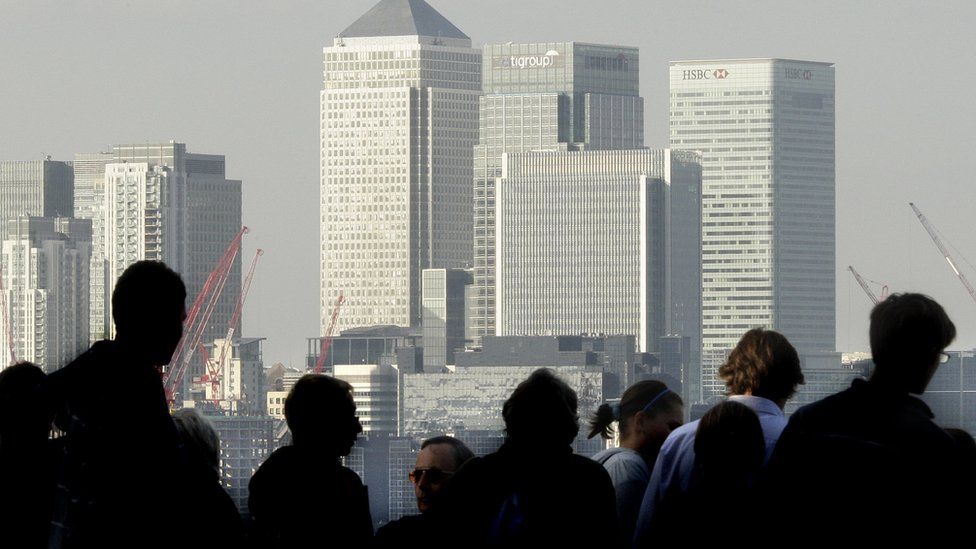 City workers silhouetted in front of the Canary Wharf skyline