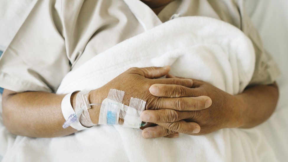 Close up iv tube on hand of senior patient sleep on the bed - stock photo
