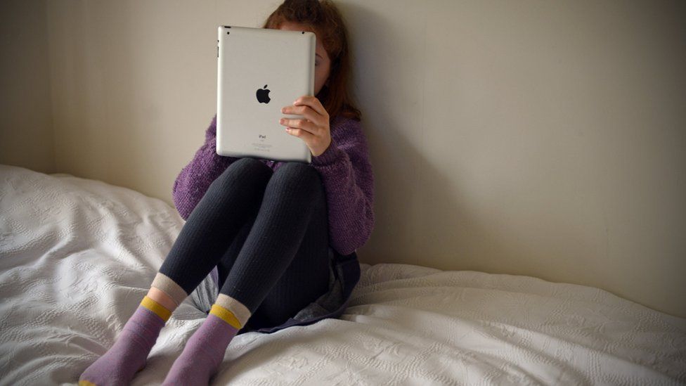 Child alone in bedroom on iPad