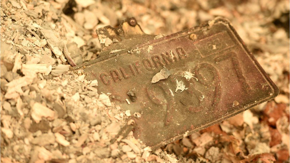 A California license plate is seen partially buried in a pile of ash at a burned residence after the Camp fire tore through the region in Paradise, California on November 12, 2018