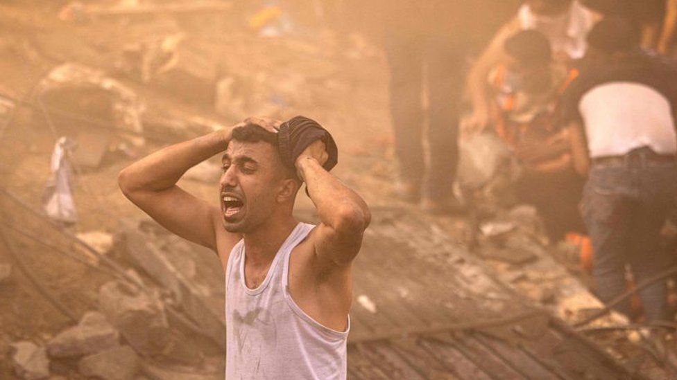 A Palestinian man reacts as others check the rubble of a building in Khan Yunis on November 6, 2023