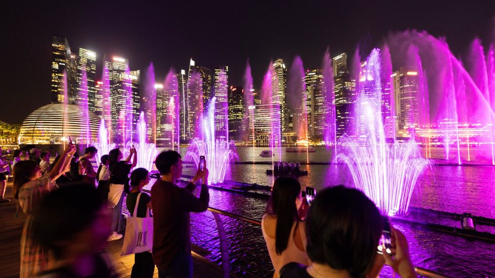 Spectators take photos of a pink water light show at Singapore's Marina Bay