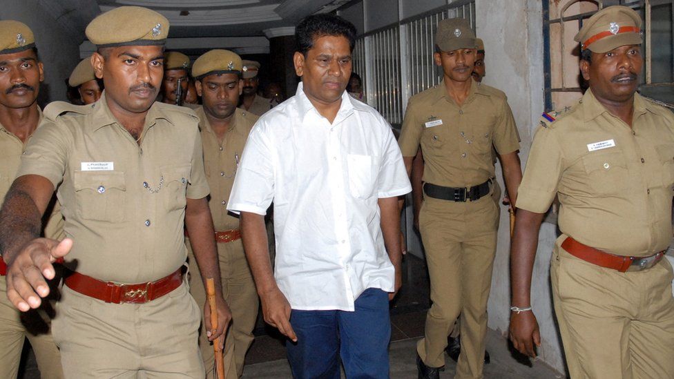 Santiago Martin, an Indian businessman, is escorted by police officers as he arrives to appear before a court in Coimbatore, India, September 8, 2011.