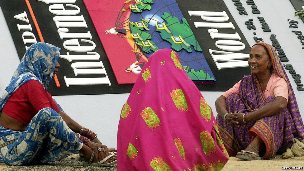 Women workers take a break in front of a banner during preparations 26 September 2000 for 'India Internet World Show 2000