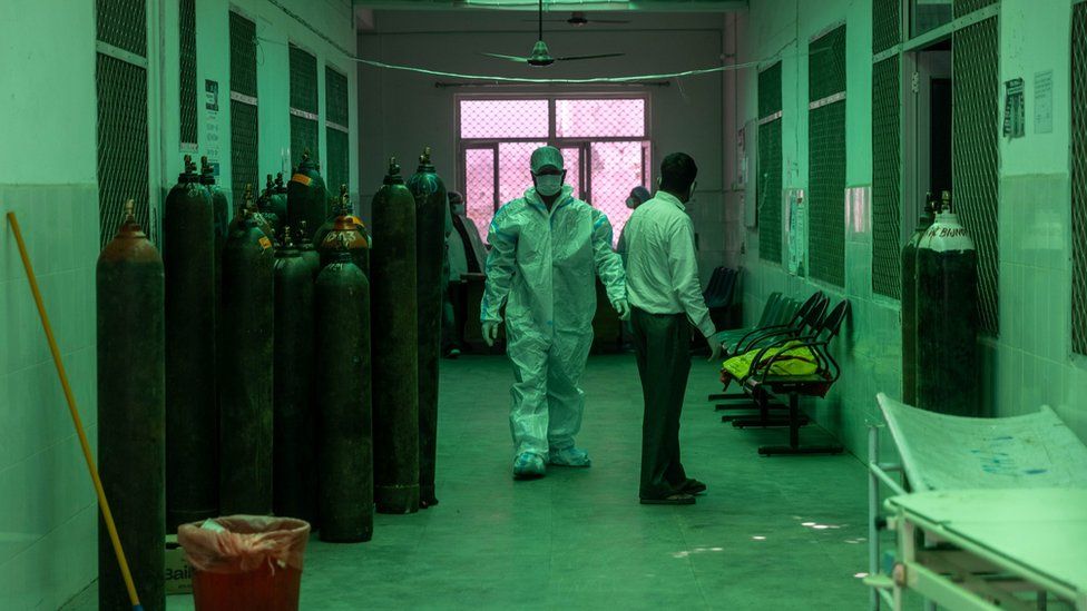 Healthcare workers in a hospital in Bijnor, Uttar Pradesh, walking past oxygen cylinders