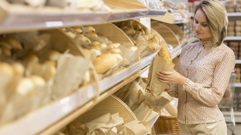 Woman looking at baguette whimsically