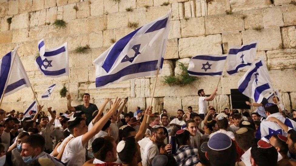 Jewish worshippers dance with Israeli national flags by the Western Wall