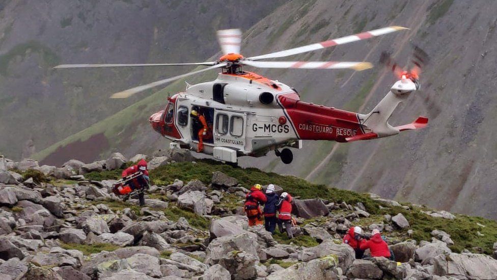 A helicopter hovers as volunteers lead a casualty towards it