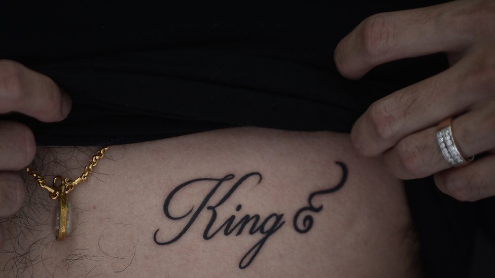 Tattoo on a man's chest reading King with the Thai number 9