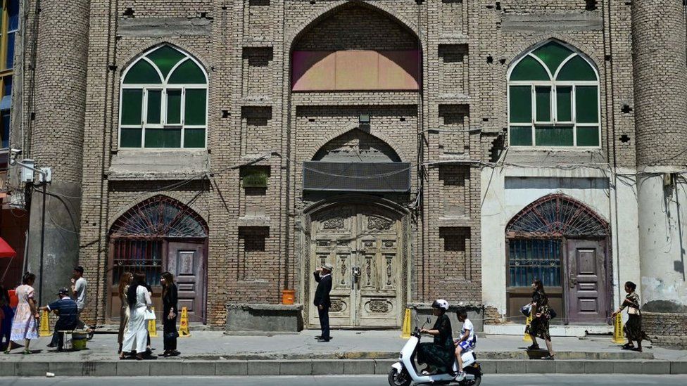 People walk in front of a disused mosque in Xinjiang, China