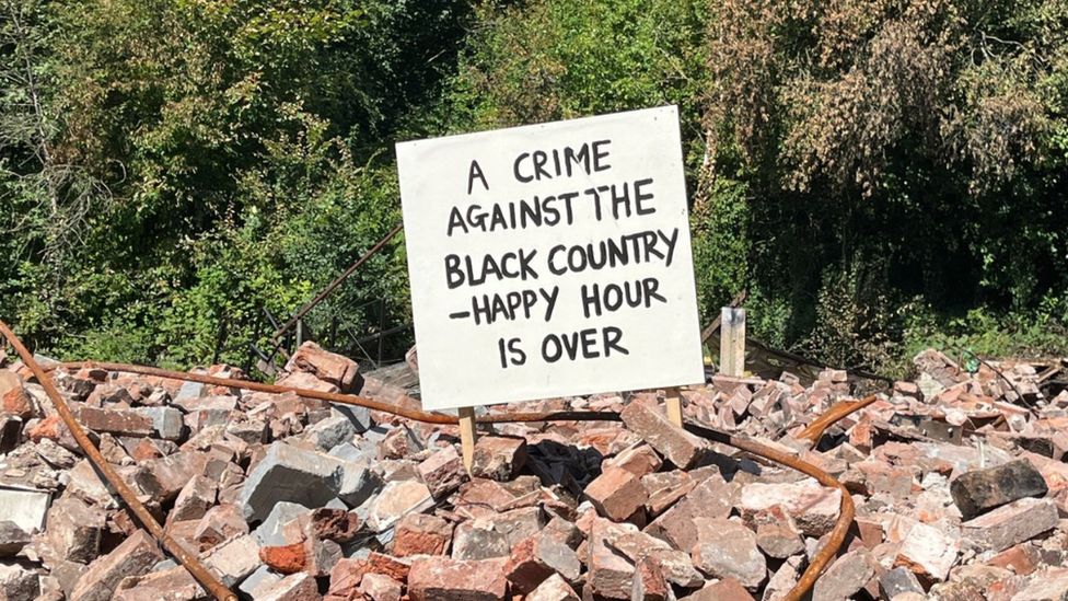 A sign sticking out of the rubble of the pub saying: 'A crime against the Black Country - happy hour is over'