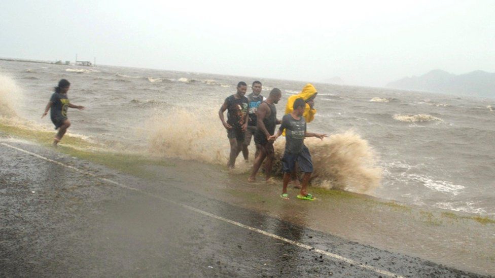 Fijians walk near the coast during a cyclone