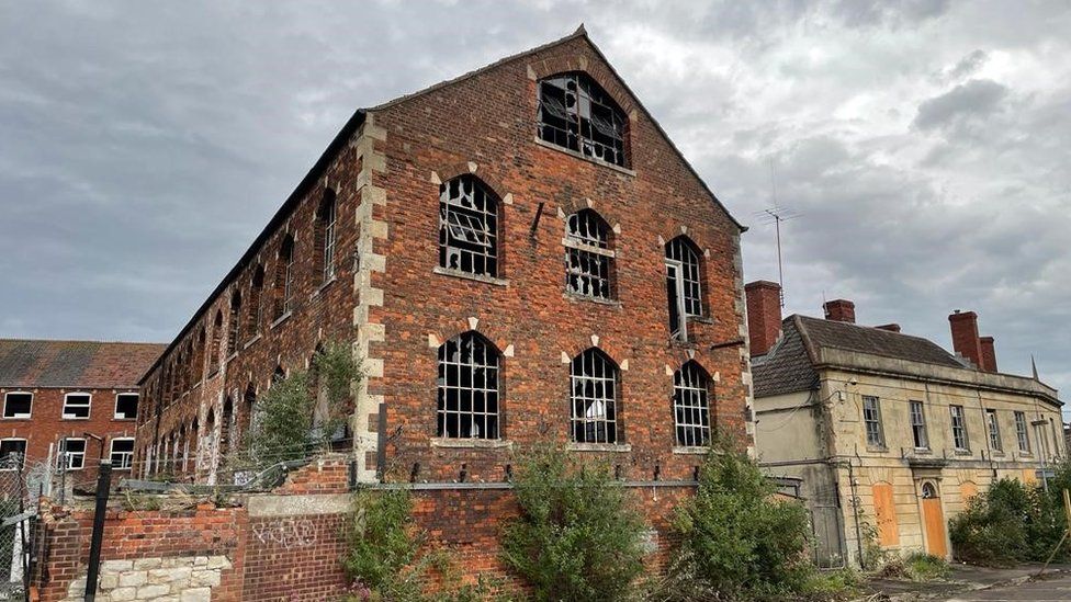 The red brick Bowyers factory building with smashed windows and boarded up doorways