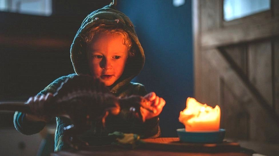 A four-year-old boy plays by candlelight at his home in Northumberland