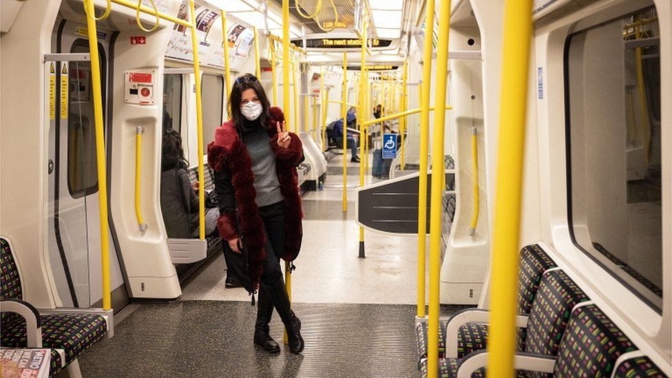 A woman wears a protective mask as she travels on an underground train in London