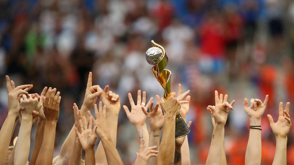 Hands of US team holding World Cup trophy