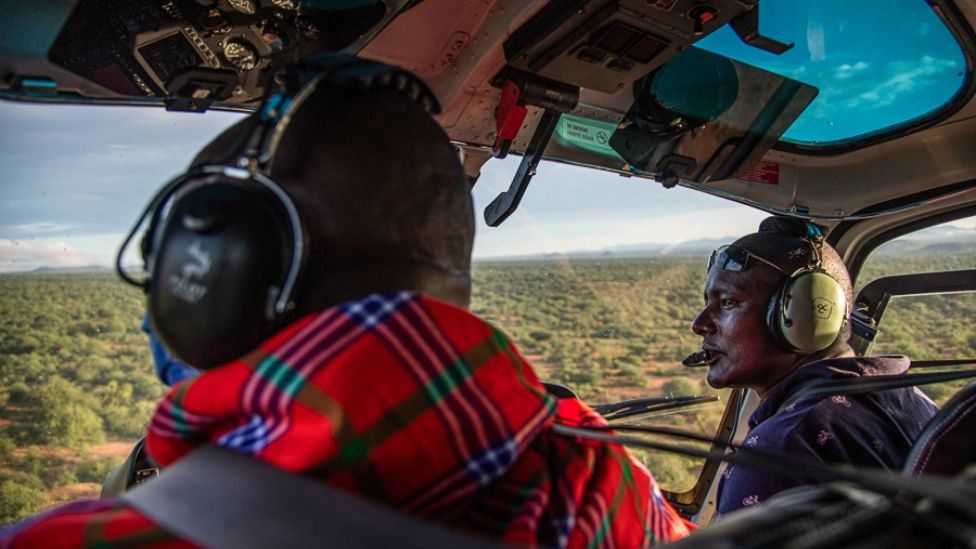 Ambrose Ngetich and Captain Iltasayon Neepe look out from the cockpit of a helicopter