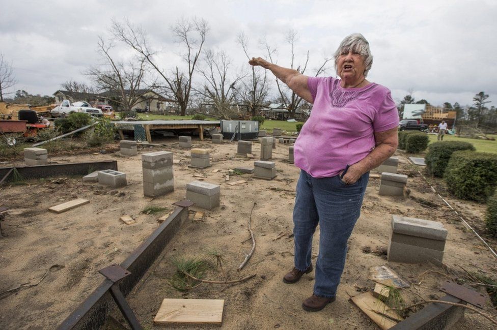 Ann Bell stands in the foundation of her son's mobile home, which was lifted in the air by a tornado