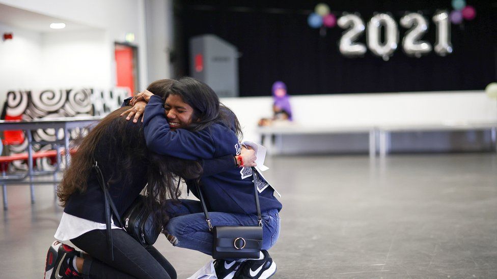 Students hug after receiving their results at Ark Academy in London