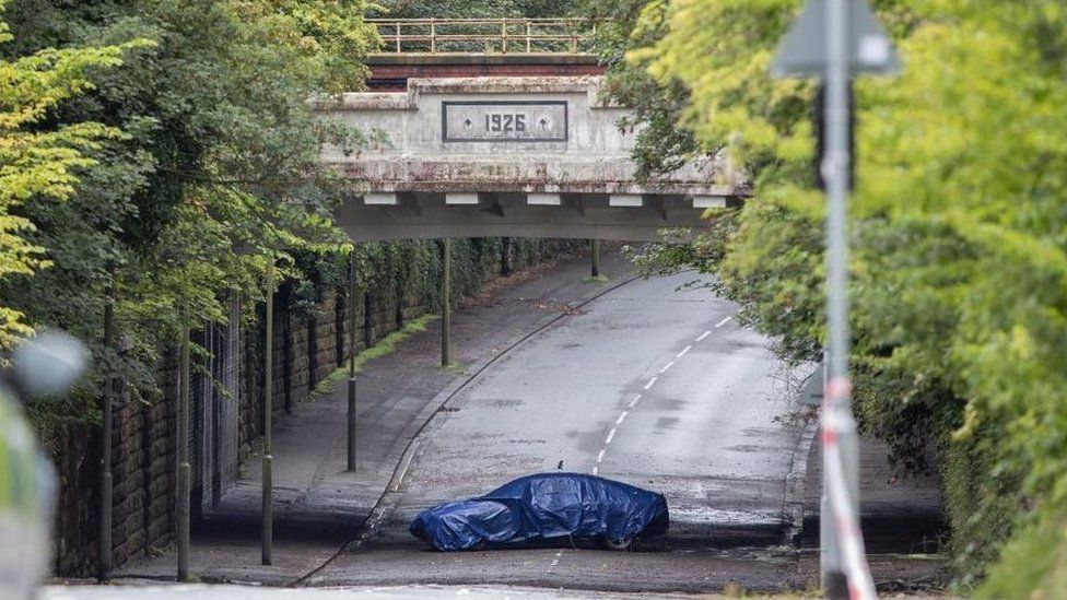 Image shows covered car under a bridge