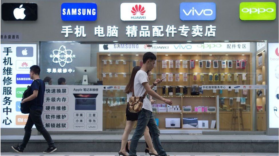 People walking past a phone shop in China