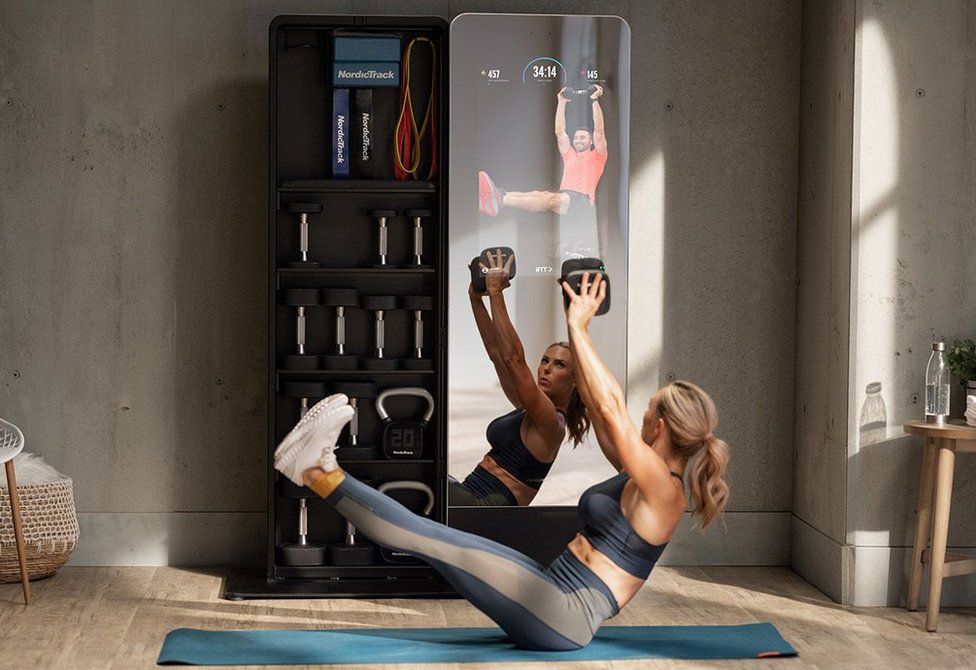 A woman using a smart fitness mirror