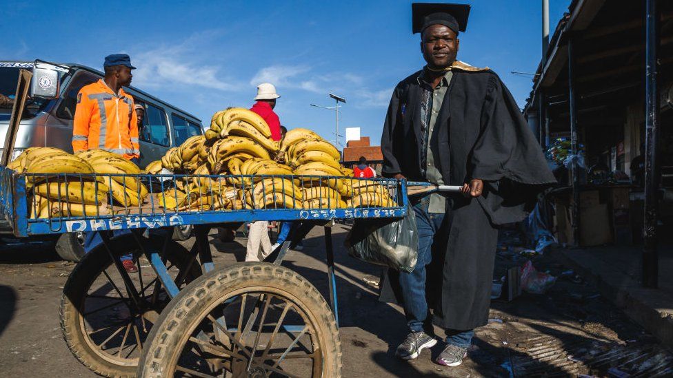 A graduate by a banana cart in Zimbabwe