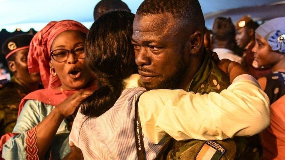 Один из 46 ивуарийских солдат, арестованных в июле и осужденных малийским правосудием и помилованных президентом переходного периода Ассими Гойтой, приветствуется родителями после церемонии в аэропорту Абиджана 7 января 2023 г.