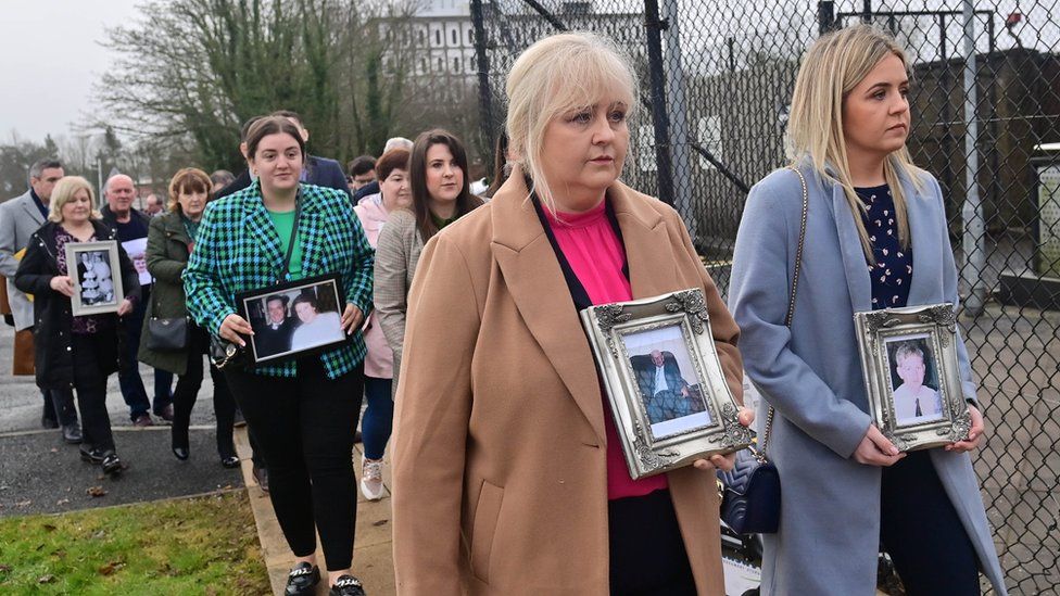 Relatives of the McKearney and Fox families carry photos of the