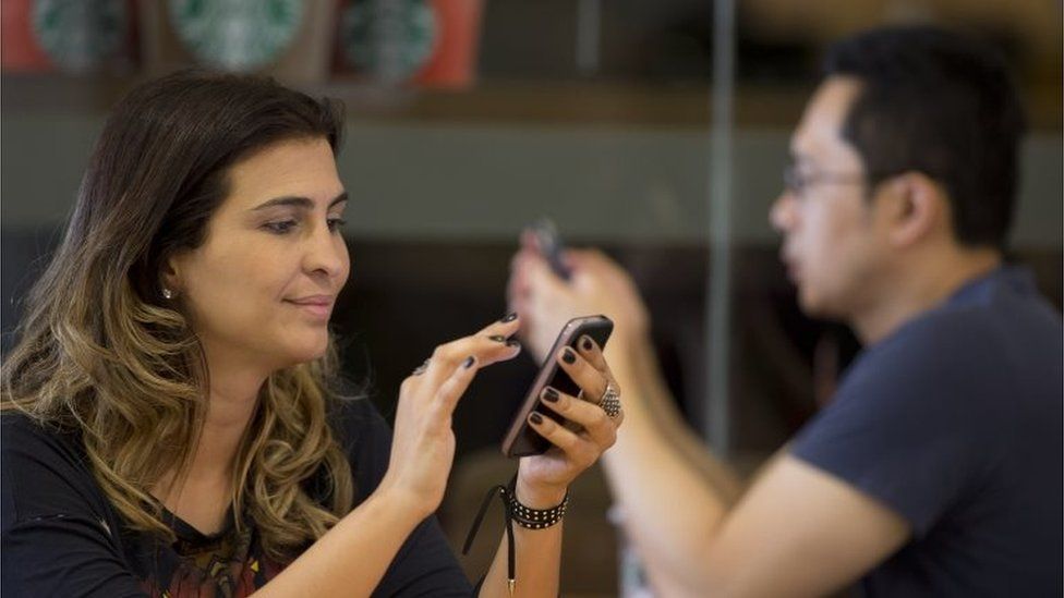 A woman checks her cell phone at a coffee shop in Sao Paulo on 17 December 2015