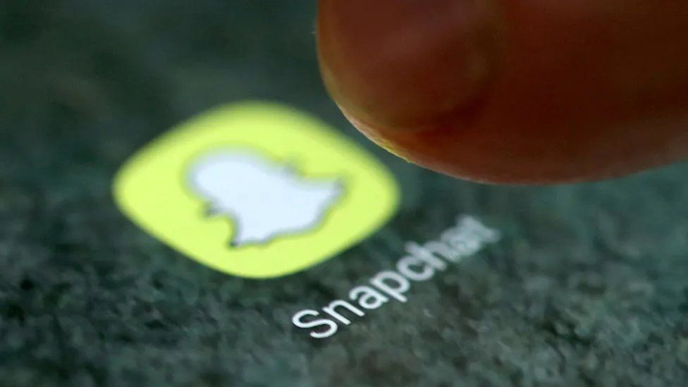 A finger hovering over the snapchat app logo