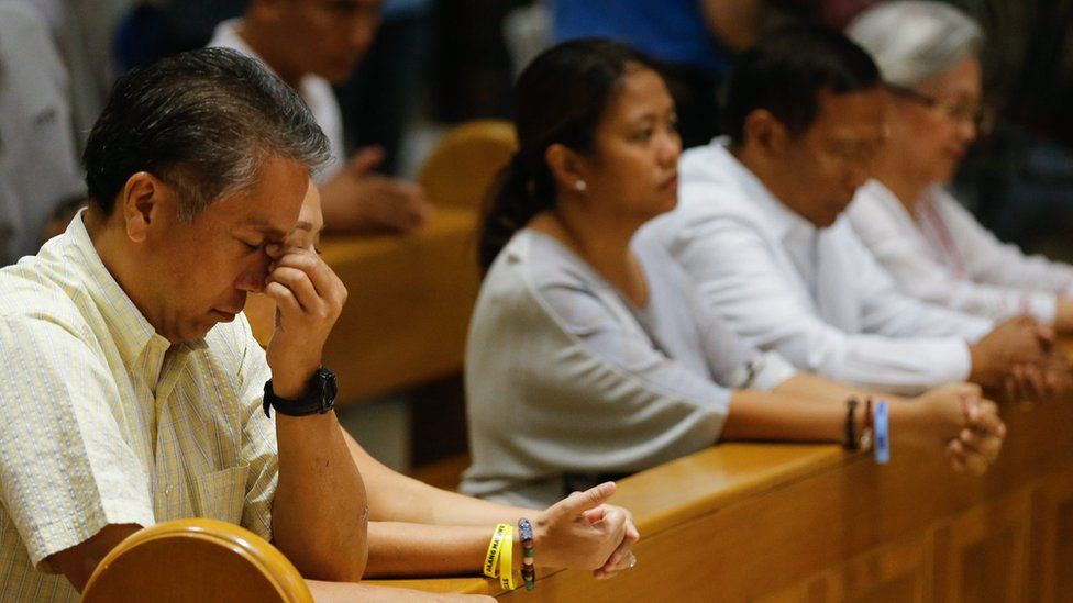 Manuel "Mar" Roxas III (left) prays in Manila Cathedral, alongside other faithful, including fellow presidential candidate Jejomar Binay (second from right)