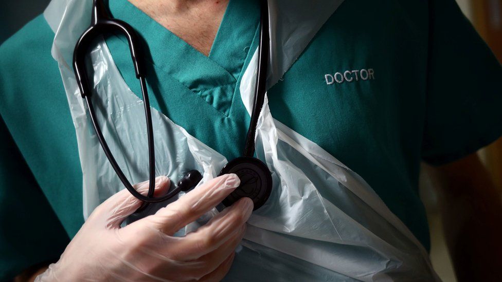 A junior doctor holding a stethoscope that is round his neck